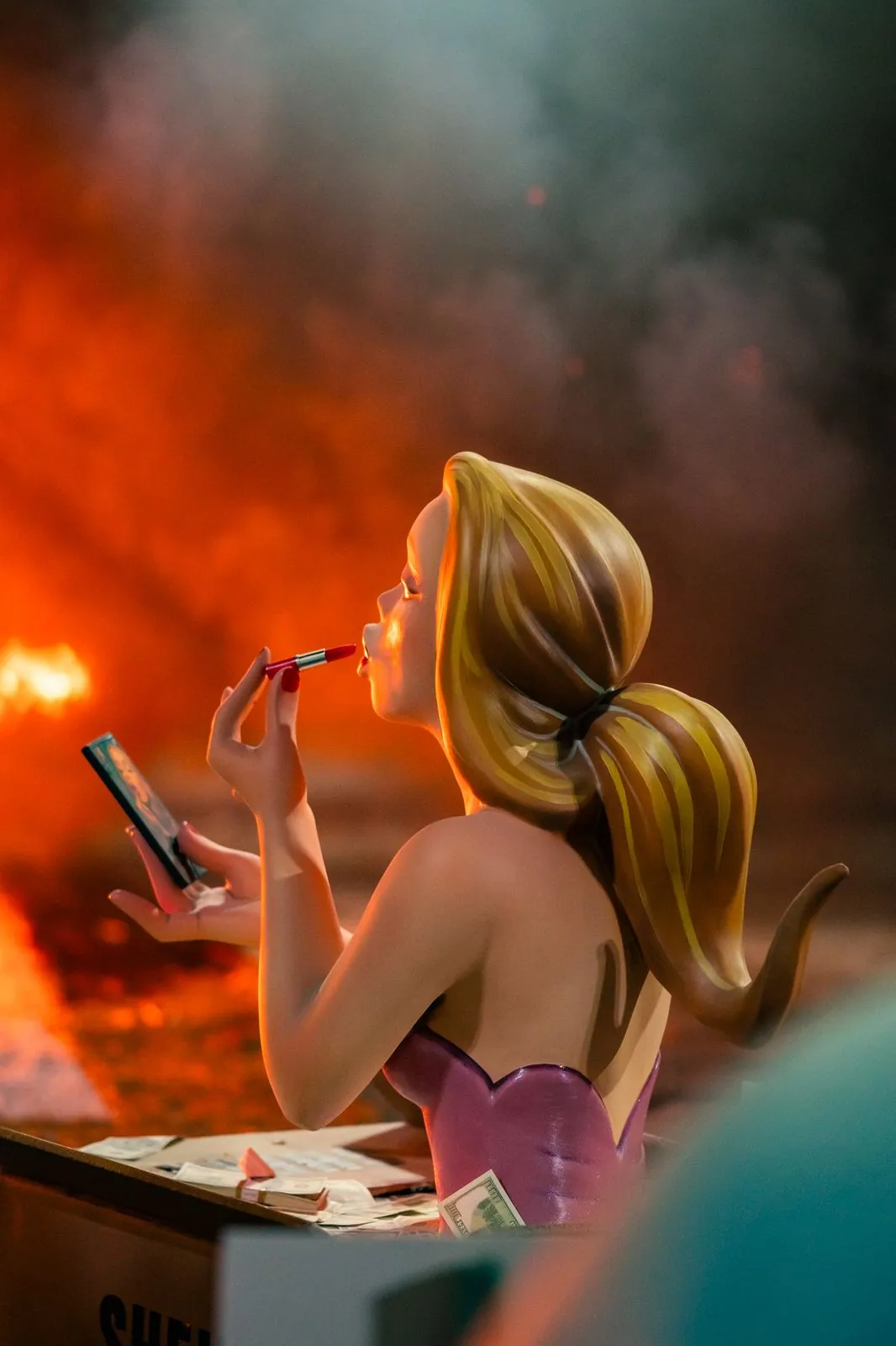 Ninot de falla pintándose los labios entre el humo